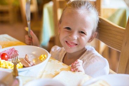 Adorable little girl having breakfast at resort restaurant