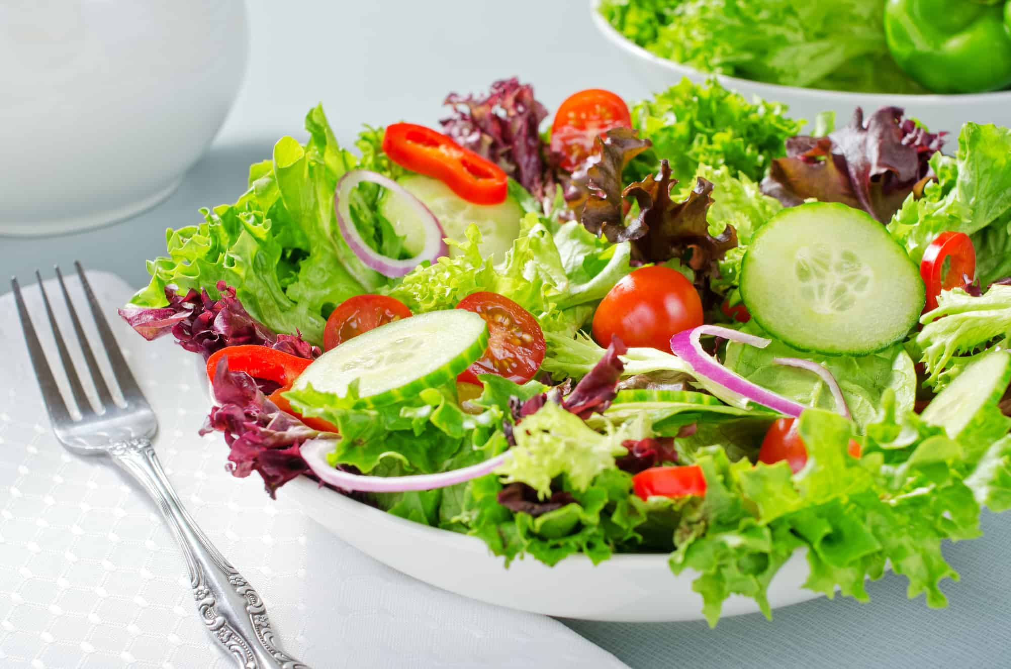 A mixed salad with lettuce, cucumber, tomatoes, red pepperm and red onion.